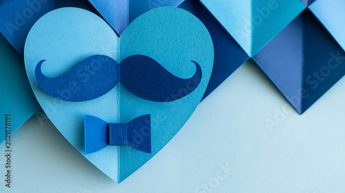 Blue paper cut heart with mustache and bow tie on geometric background, creative Fathers Day greeting concept, handmade masculine love symbol with elegant copy space