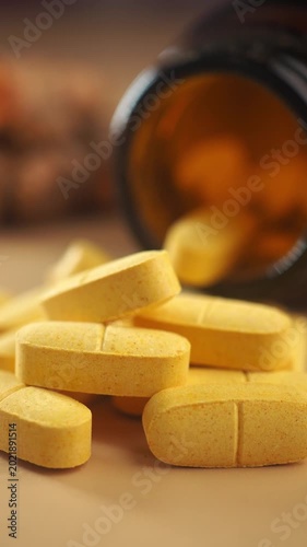 Yellow pills spilled from a brown bottle on a table