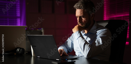Photos Business man working overtime in a dark office late at night