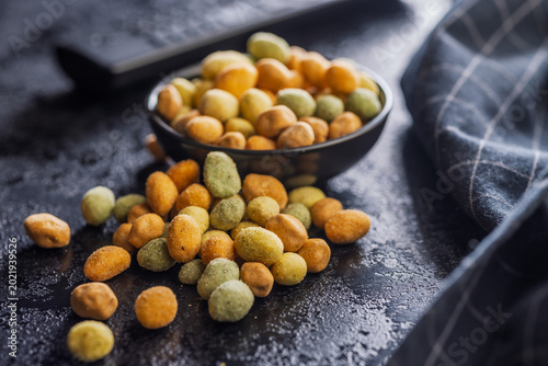 Crunchy Wasabi Peas and Coated Peanuts in a Bowl - Spicy Snack Mix on Dark Surface