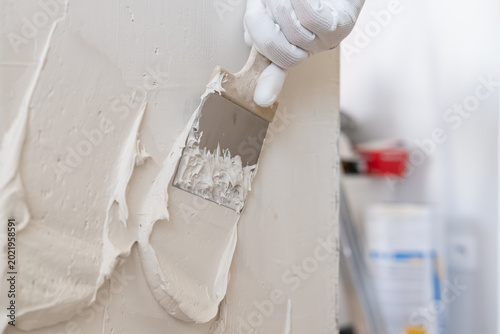 Valokuva Applying smooth plaster to wall surface using stainless steel trowel in construction setting