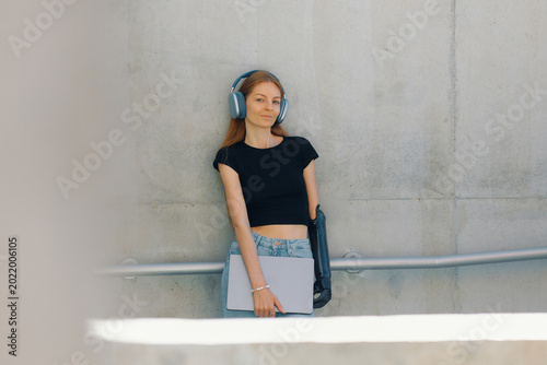 Woman with bionic prosthesis stands while holds a laptop in a modern setting