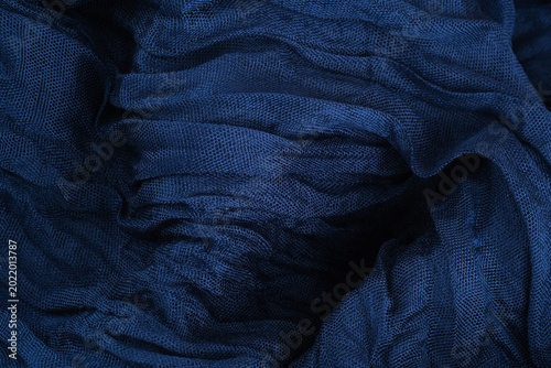 Crinkled linen fabric texture with flowing folds in dark blue