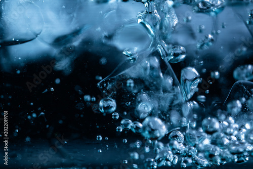 Close up of ice cubes underwater with oxygen bubbles, frost patterns, and soft light reflections. Concepts for beauty advertising, menu designs for bars and restaurants, cryotherapy.