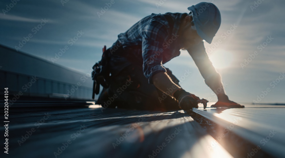 Fototapeta premium Roofer Installing Solar Panels on a Commercial Building Rooftop at Sunset