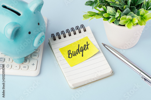 Budget note with piggy bank on calculator and pen on desk, financial planning, personal budgeting, and money management