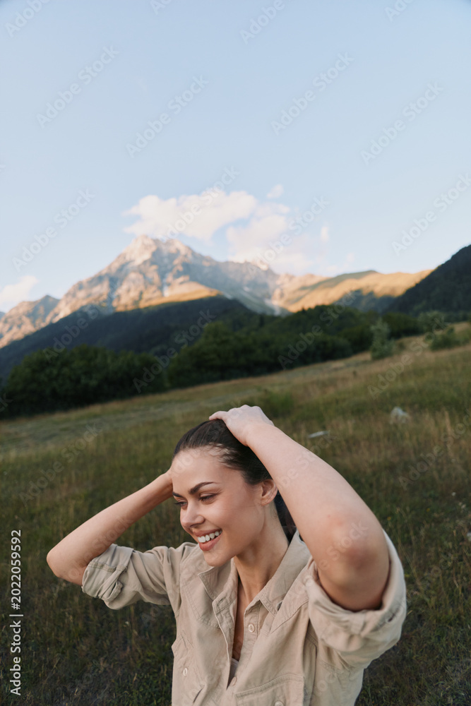 Fototapeta premium Woman enjoying outdoor lifestyle in a grassy field with distant mountains, smiling and relaxed, embodying nature, happiness, and summer vibe in a bright countryside setting