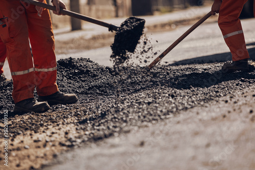 Construction worker working on a new asphalt layer on a public street.