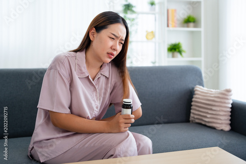 Bild auf Leinwand Young woman with bottle of pills suffering from abdominal pain.