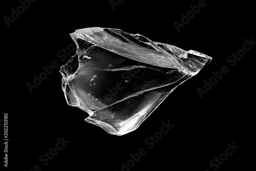 Fotografija Broken transparent glass shard isolated on a black background, with sharp cracked edges, glossy reflections, and dramatic high-contrast studio lighting