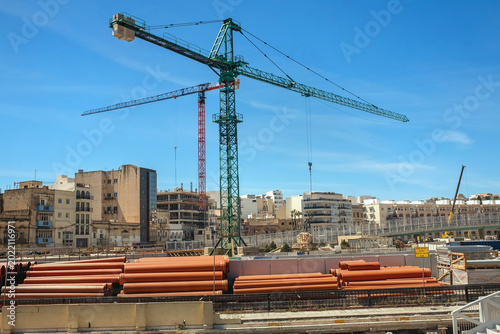 Fotografía Tall tower cranes and building materials at an urban construction site