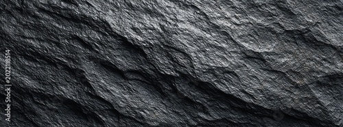 Textured close-up of dark grey, rough stone with visible layered details
