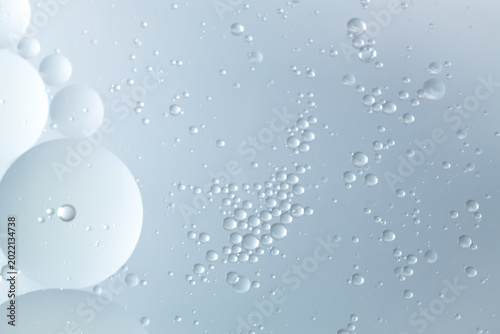 Abstract photo of water and oil droplets resembling lotion and cream texture on soft blue background. Perfect for skincare, beauty, and science themes.