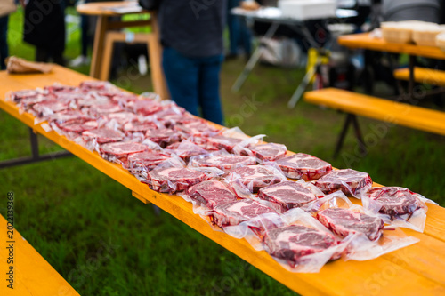 Rows of raw, marbled ribeye steaks laid out on butcher paper during a Steak Cookoff Association (SCA) BBQ competition, showcasing premium meat quality and preparation for professional grilling.