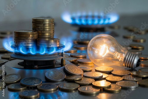 Light bulb on and lit gas cooker, with coins next to it. Energy and gas costs, cost increases.

