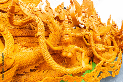 Billede på lærred Stunning yellow wax sculpture featuring beautiful mythical female figures holding a Naga tail during a candle parade