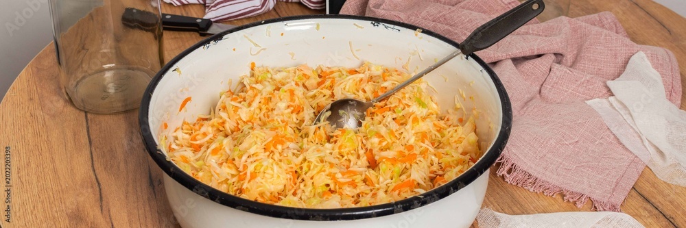 Φωτογραφία Cabbage and carrots are mixed together for fermentation in a bowl on a wooden table