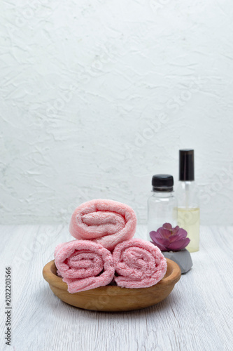 A white table with pink towels, a houseplant, shampoo, condition