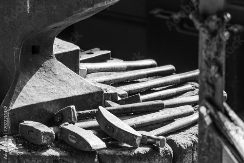 Fotografi Blacksmith anvil and hammer in black and white with strong contrast