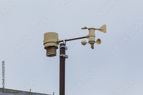 Fotografie A weather station with a sensor and anemometer mounted on a pole against a clear sky