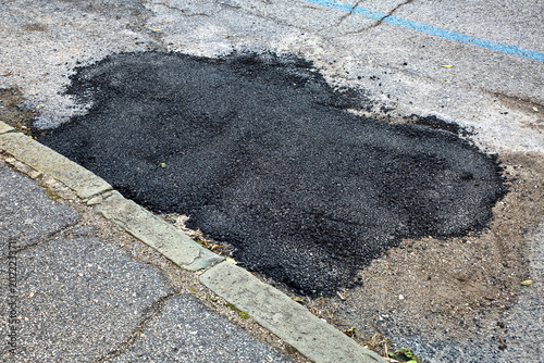 OLD BROKEN ASPHALT ROAD with dangerously damaged asphalt that has potholes dangerous for the transit of motor vehicles - Old damaged and worn asphalt road with pothole filled with new bitumen