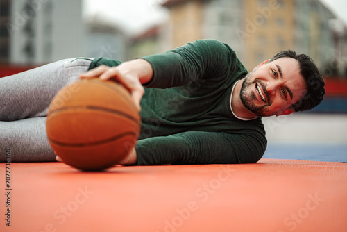 Photos Lying man on basketball court smiling holding ball