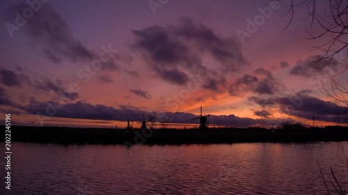 Traditional Dutch Windmill Silhouettes Against Vibrant Red Sunset Sky