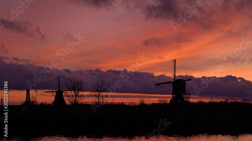 Traditional Dutch Windmill Silhouettes Against Vibrant Red Sunset Sky