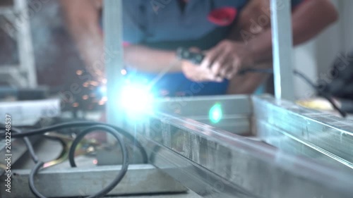 Blurred of welder at work for background. A local Thai welder working on a steel box beam at an outdoor construction site. The worker is seen wearing sunglasses for eye protection while manual arc.