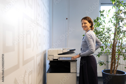 Woman operating a modern canon multifunction printer in a corporate office, managing business documents