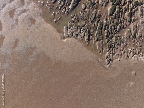 Tableau sur toile Coastal rocky beach terrain with exposed boulders, wet sand textures and open se
