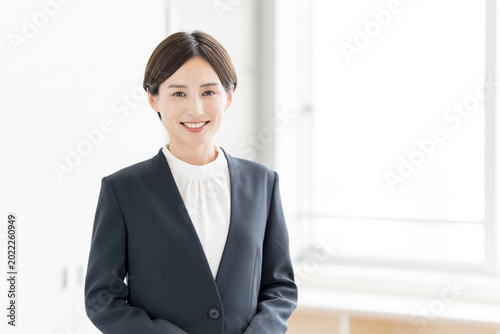 カメラ目線で微笑むジャケットを着た日本人女性ビジネスパーソン