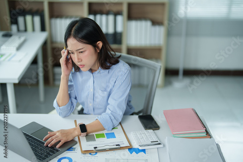 Billede på lærred Stressed asian business woman experiencing a severe headache and burnout while w