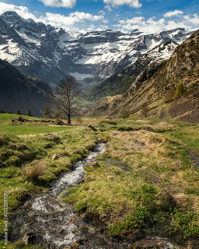 Mountain stream cascades down in the French Pyrenees with the Cirque de Gavarnie in the distance
