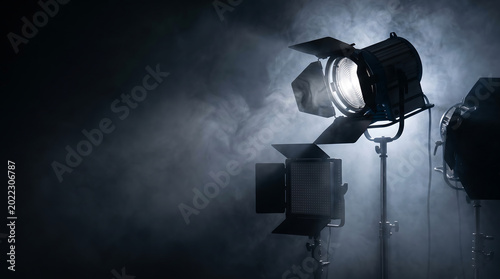 Cinematic stage spotlights shining bright beams through smoke in a dark professional studio