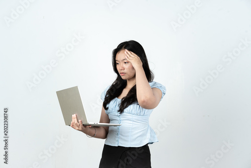 Stressed young Asian woman holding laptop having headache or work problem isolated on white