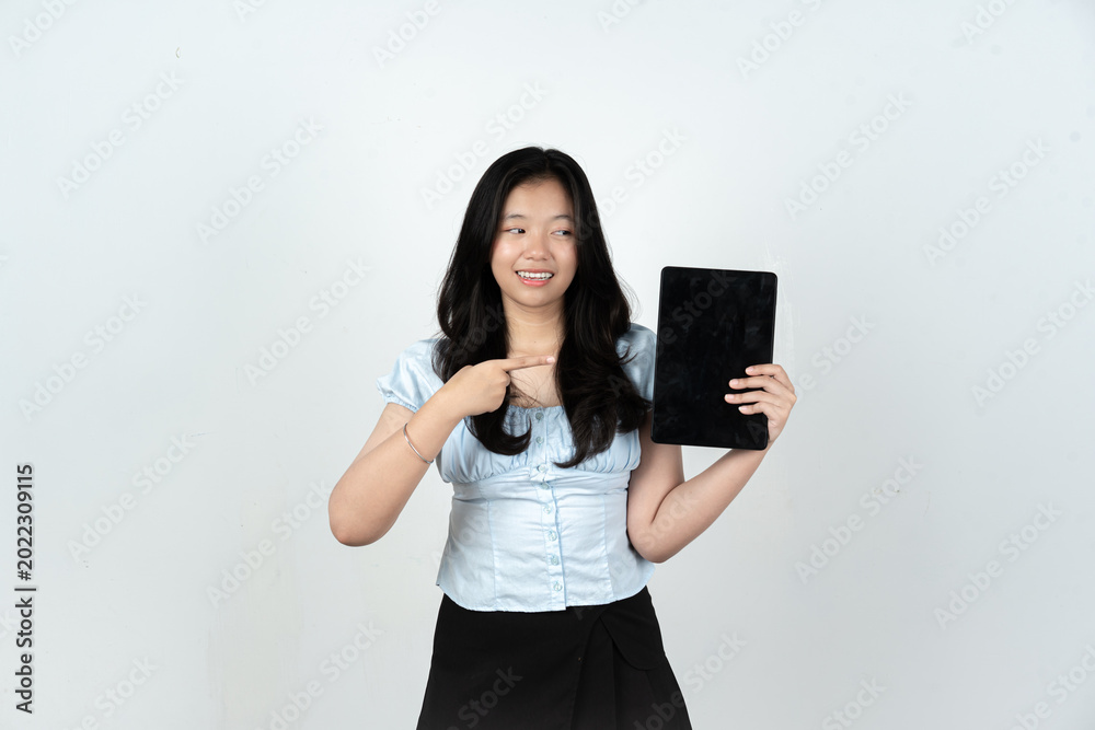 Naklejka premium Smiling Asian female student pointing at tablet screen and looking sideways