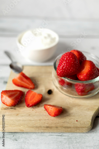 Fresh white yogurt dip with ripe strawberries for breakfast.
