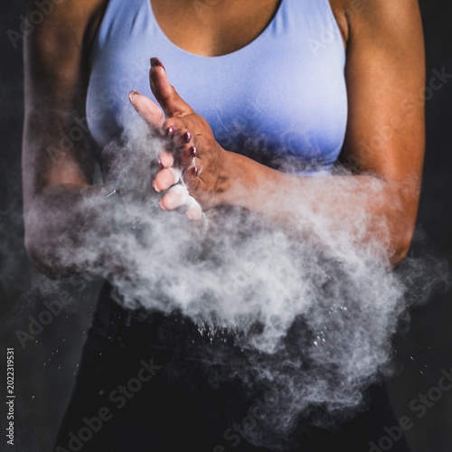 Foto Person in athletic wear clapping hands with chalk dust in the air