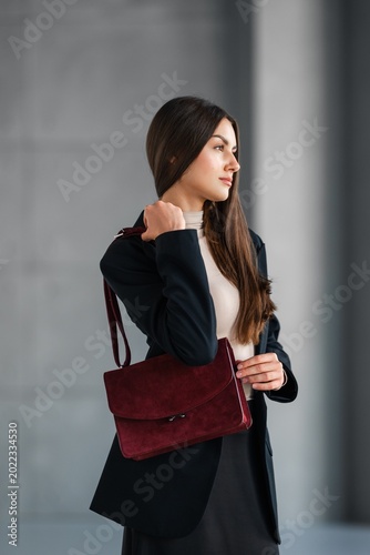 Product Focused Woman Holding Suede Bag Against Neutral Outfit, Burgundy Satchel, Sharp Tailoring, Soft