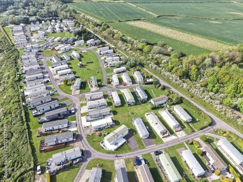 Schilderij op canvas Aerial sweep over holiday caravan area beside wide coastal scenery and warm natu