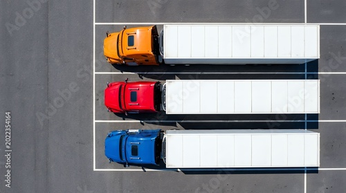 Aerial view of colorful semi trucks parked in marked parking spaces at logistics yard
