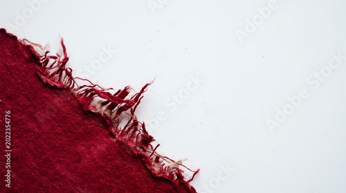 Close up of red fabric with frayed edges on white background showcasing texture and detail