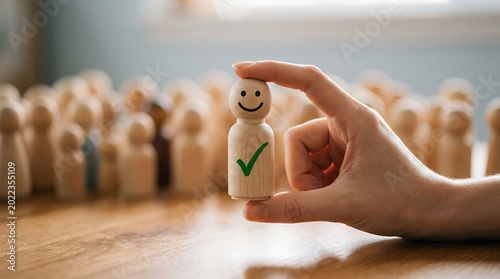 Concept of selecting happy wooden figure with checkmark among blurred crowd of figures
