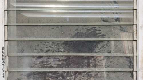 Photos A dirty glass louver window covered in thick dust and stains