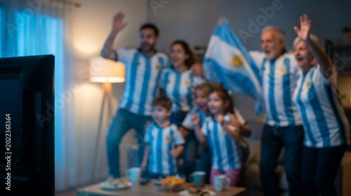 Argentine family cheering in jerseys with flag in living room intentationally blurred football Argentina fan celebration background