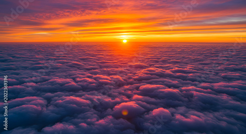 Sunset illuminates a vast layer of clouds from above the horizon in a serene sky.
