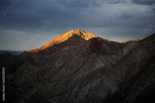 Quadro su tela Majestic Rocky Mountain with Golden Alpenglow and Dramatic Stormy Sky at Dusk