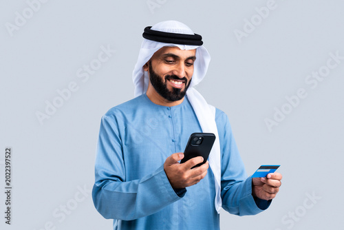 Emirati man making online payment with smartphone and credit card