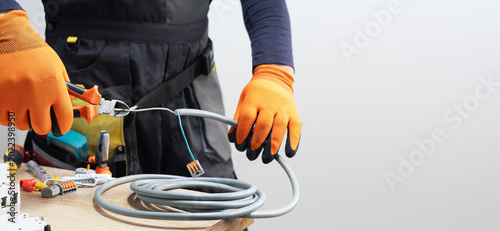 Foto Electrician at work with nippers in hand cut the electric wire